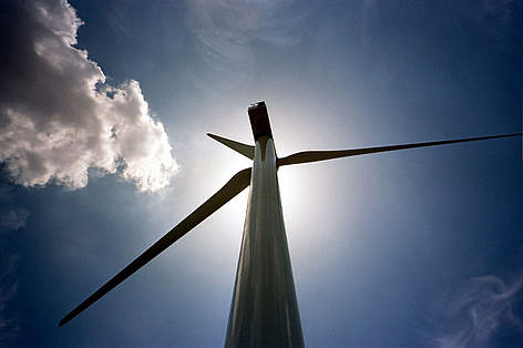 Detalhe de turbina contra o sol, e atrás o céu azul no parque eólico de Castilla-La Mancha, Espanha. rel=